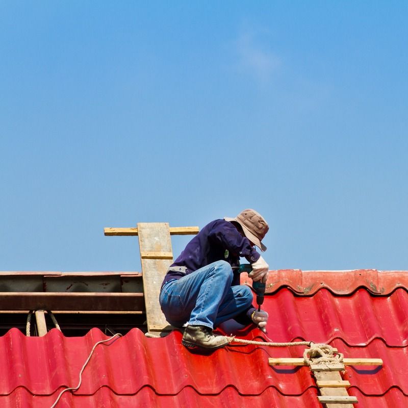 albañil realizando labores de construccion sobre tejado rojo